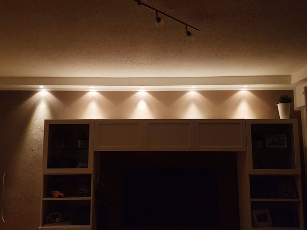 Wohnwand mit indirekter LED-Hintergrundbeleuchtung und Einbauspots im Wohnzimmer