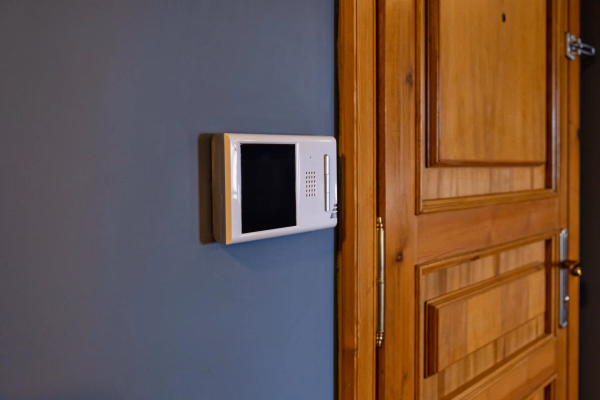 Video-Gegensprechanlage mit Monitor neben einer Holztür an einer grauen Wand