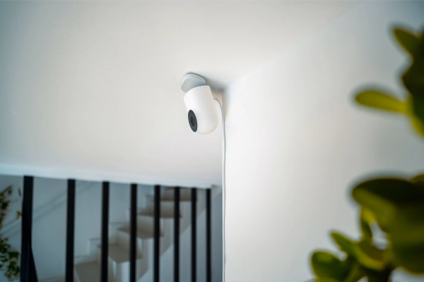 Kleine weiße IP-Überwachungskamera an einer Deckenwand in einem modernen Innenraum