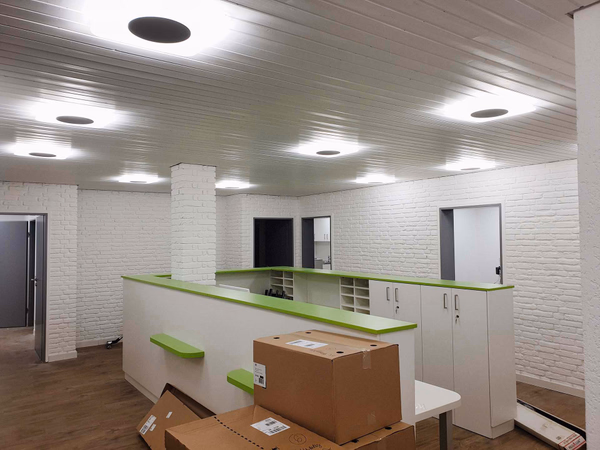 Frisch umgebauter Gewerberaum mit grüner Empfangstheke und neu installierter LED-Deckenbeleuchtung